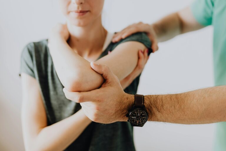 Therapist stabilizing a patient's arm during shoulder therapy session.